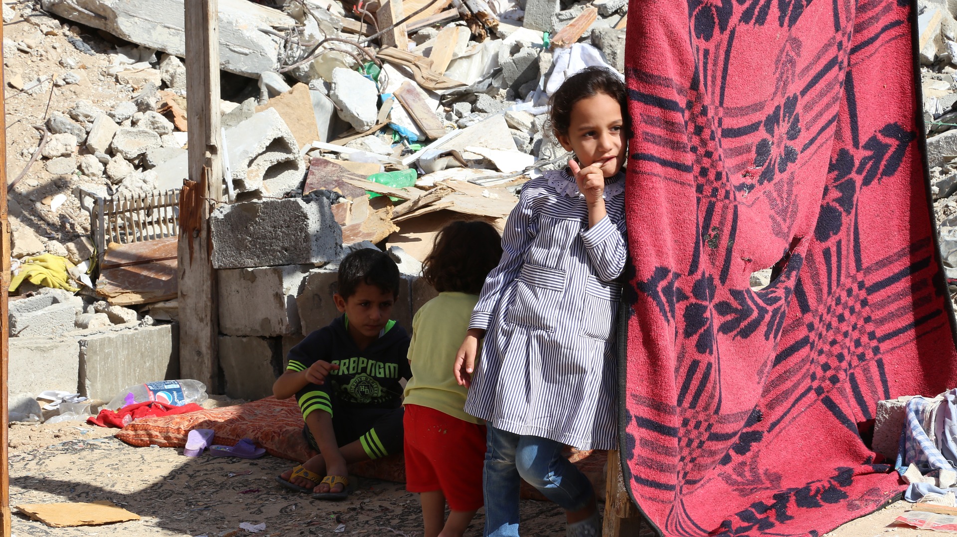 Palästinensische Kinder im Gazastreifen vor wahrscheinlich durch Israel mit Bombenangriffen zerstörten Häusern.