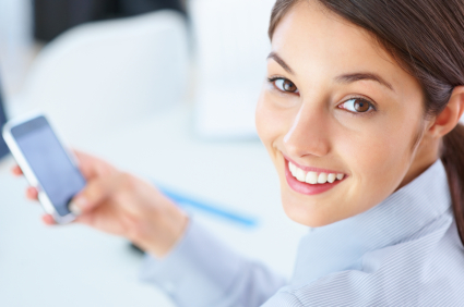 Closeup of female executive using mobile phone and giving you cute smile