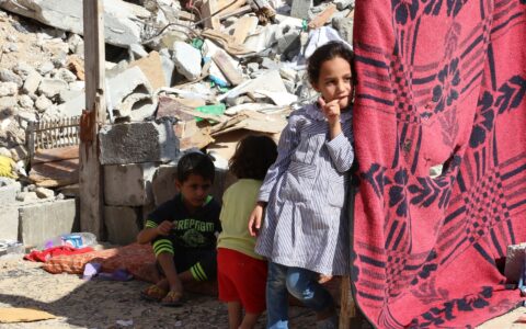 Palästinensische Kinder im Gazastreifen vor wahrscheinlich durch Israel mit Bombenangriffen zerstörten Häusern.