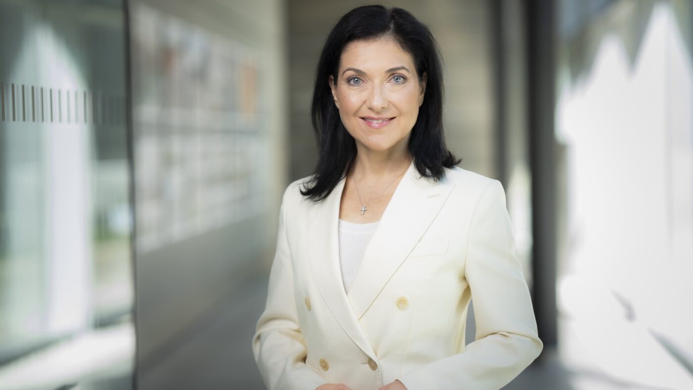 Porträtaufnahme von Bundeswirtschaftsministerin Katherina Reiche in hellem Blazer in einem Gebäudeflur.