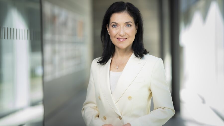 Porträtaufnahme von Bundeswirtschaftsministerin Katherina Reiche in hellem Blazer in einem Gebäudeflur.