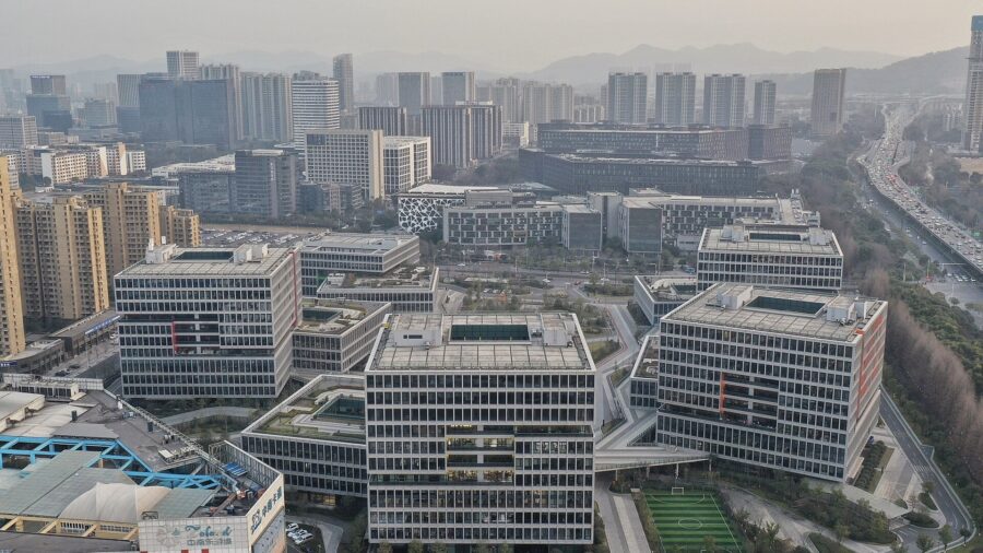 Luftaufnahme eines Bürocampus mit mehreren hellen, gestuften Gebäuden, dahinter die Hochhäuser von Hangzhou.