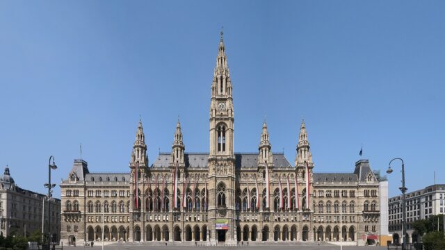 Das Wiener Rathaus mit beflaggter Hauptfassade, aufgenommen bei klarem Himmel vom Rathausplatz aus