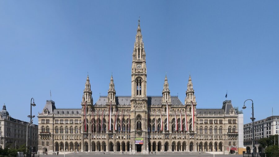 Das Wiener Rathaus mit beflaggter Hauptfassade, aufgenommen bei klarem Himmel vom Rathausplatz aus