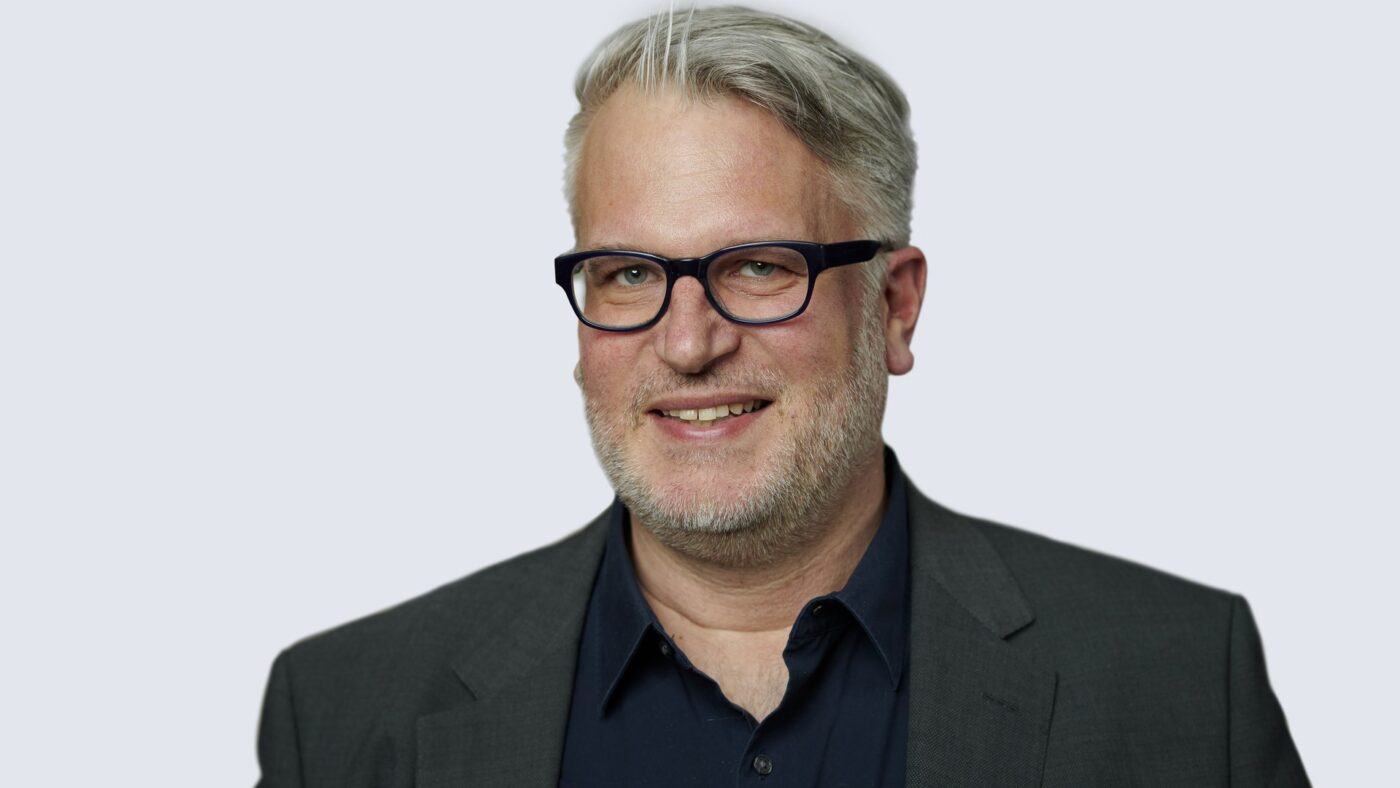 Portraitaufnahme von Markus Blumenthal-Beier, Bundesvorsitzender des Hausärztinnen- und Hausärzteverbandes, vor hellem Hintergrund