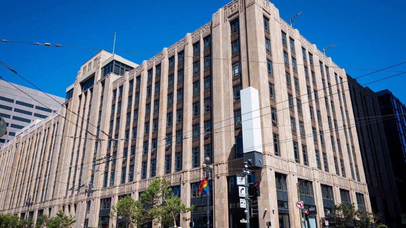 Eckansicht des Gebäudes der X-Zentrale an der Market Street in San Francisco vor blauem Himmel; an der Gebäudeecke eine leere weiße Säule ohne Schriftzug