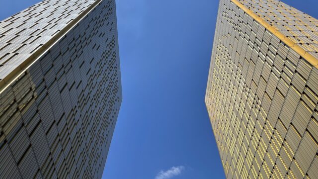 Die beiden goldfarbenen Tuerme des Gerichtshofs der Europaeischen Union in Luxemburg aus der Froschperspektive vor blauem Himmel.