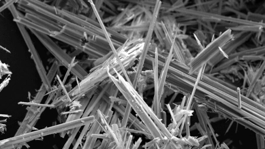 Rasterelektronenmikroskopische Aufnahme dicht gebuendelter, nadelfoermiger Anthophyllit-Asbestfasern vor schwarzem Hintergrund