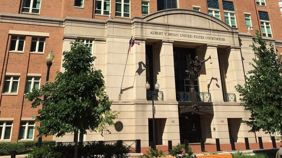 Eingangsbereich eines Gerichtsgebaeudes aus Backstein und hellem Naturstein mit der Inschrift Albert V. Bryan United States Courthouse und einer Justitia-Figur ueber dem Portal