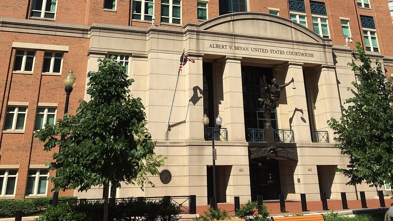 Eingangsbereich eines Gerichtsgebaeudes aus Backstein und hellem Naturstein mit der Inschrift Albert V. Bryan United States Courthouse und einer Justitia-Figur ueber dem Portal