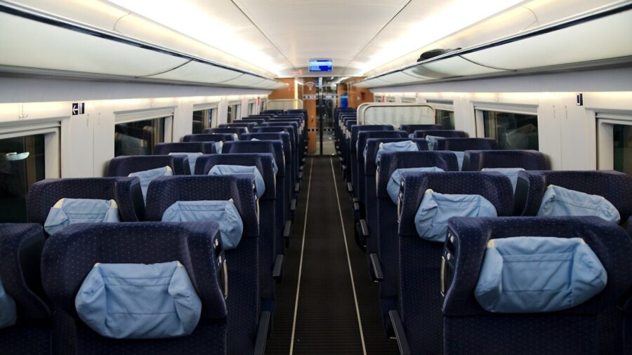 Leerer Großraumwagen der 2. Klasse in einem ICE der Deutschen Bahn, Blick durch den Mittelgang auf Sitzreihen mit kleinen Reservierungsanzeigen an den Rückenlehnen.