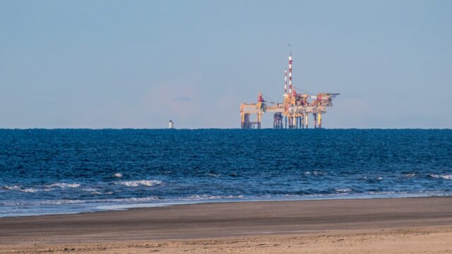 Erdgasförderplattform auf offener See vor einem Sandstrand, aufgenommen von der niederländischen Insel Ameland aus