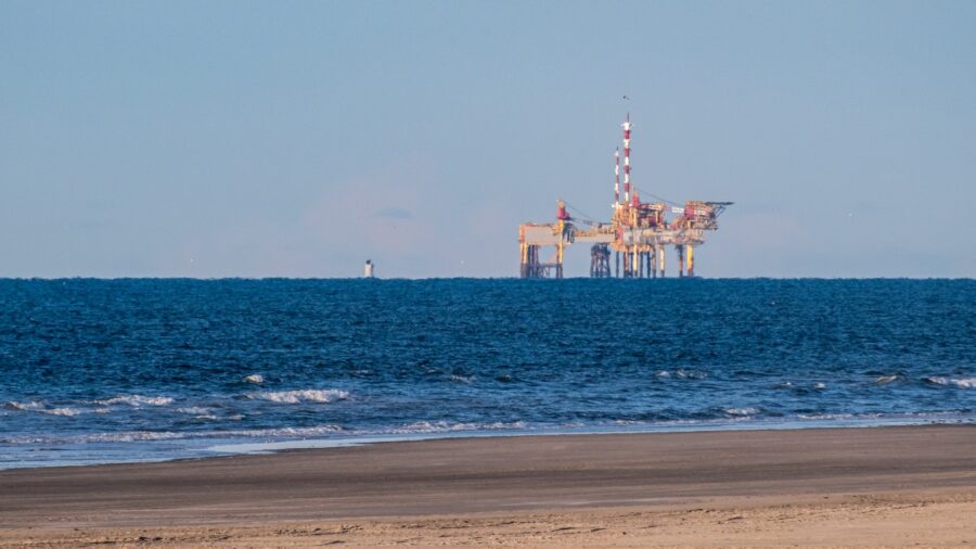 Erdgasförderplattform auf offener See vor einem Sandstrand, aufgenommen von der niederländischen Insel Ameland aus