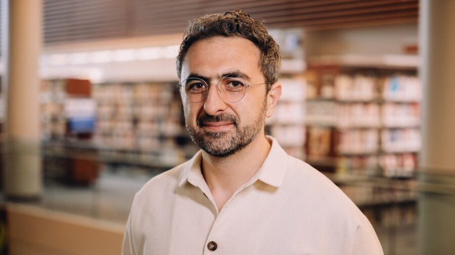 Porträtaufnahme von Mustafa Suleyman, Chef der Microsoft-Sparte Microsoft AI, vor einem unscharfen Bücherregal
