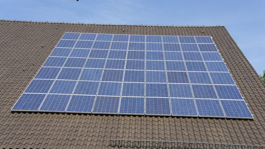 Photovoltaikmodule auf dem Ziegeldach eines Wohnhauses unter blauem Himmel