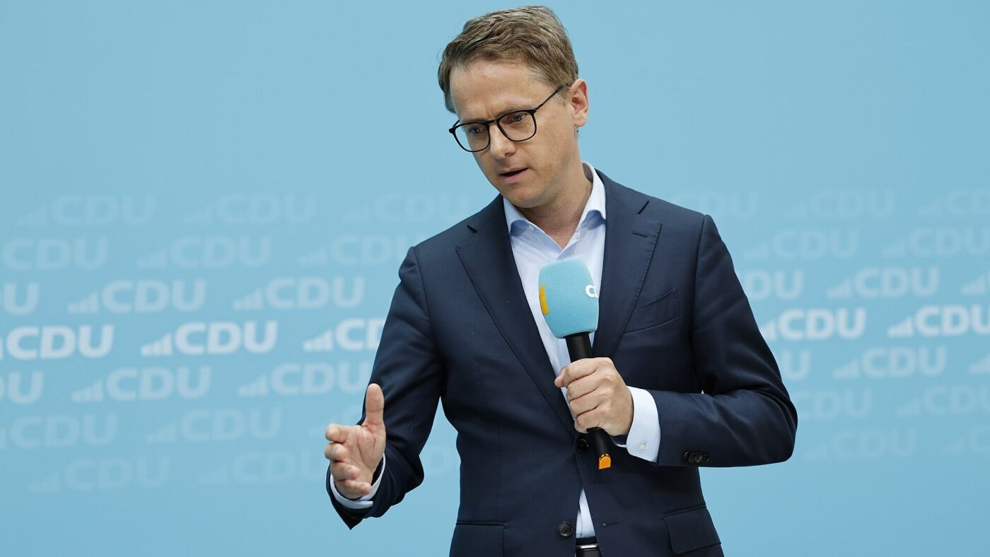 Carsten Linnemann steht mit einem Mikrofon in der Hand vor einer hellblauen Wand mit CDU-Schriftzuegen.