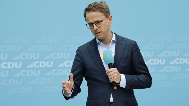 Carsten Linnemann steht mit einem Mikrofon in der Hand vor einer hellblauen Wand mit CDU-Schriftzuegen.