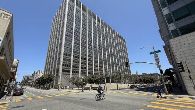 Das Phillip Burton Federal Building und United States Courthouse an der Ecke Golden Gate Avenue und Polk Street in San Francisco, ein hoher Bürobau mit Rasterfassade unter blauem Himmel