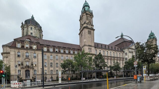Neobarockes Gerichtsgebaeude des Kriminalgerichts Moabit in der Turmstrasse in Berlin mit Uhrturm und gruenen Kuppeln, davor eine regennasse Strasse