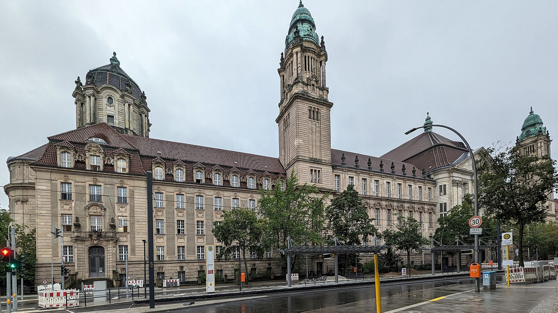 Neobarockes Gerichtsgebäude des Kriminalgerichts Moabit in der Turmstraße in Berlin mit Uhrturm und grünen Kuppeln, davor eine regennasse Straße