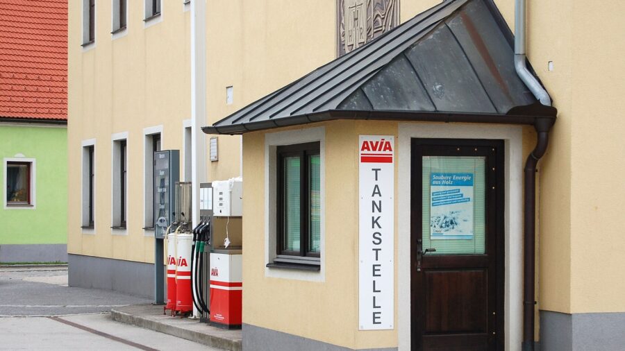 Kleine Tankstelle mit zwei Zapfsaeulen an einem gelben Wohnhaus in einem niederoesterreichischen Ort