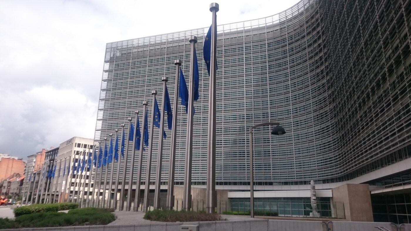 Das Berlaymont-Gebäude in Brüssel mit einer Reihe von Europaflaggen davor, Sitz der Europäischen Kommission