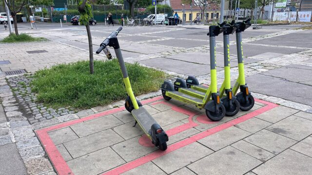 Vier Leih-E-Scooter stehen auf einer rot markierten Abstellfläche auf einem Gehsteig in Wien-Ottakring.