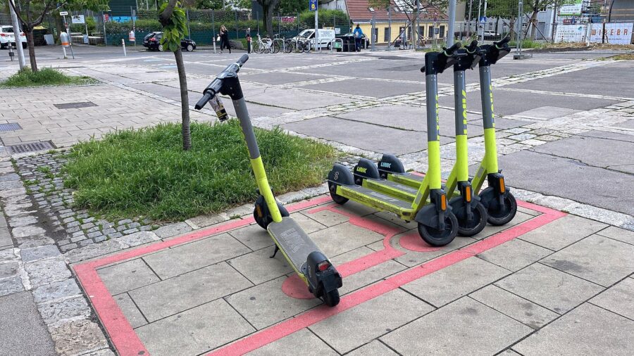Vier Leih-E-Scooter stehen auf einer rot markierten Abstellfläche auf einem Gehsteig in Wien-Ottakring.