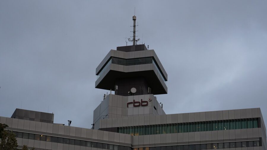 Das Sendezentrum des Rundfunks Berlin-Brandenburg in Berlin mit dem rbb-Schriftzug unterhalb des auskragenden Turmgeschosses, aufgenommen bei bedecktem Himmel.
