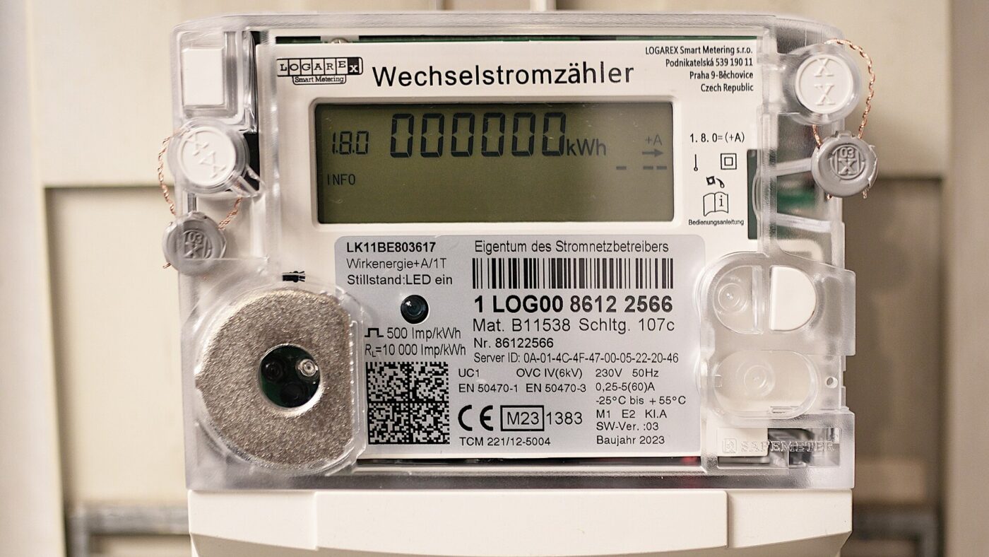 Digitaler Wechselstromzähler in einem Zählerschrank, das Display zeigt einen Zählerstand von 000000 Kilowattstunden am Tag des Einbaus.