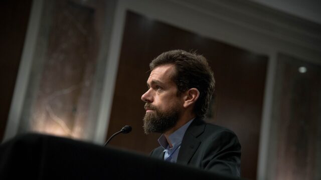 Jack Dorsey sitzt an einem Tisch vor einem Mikrofon und blickt zur Seite.