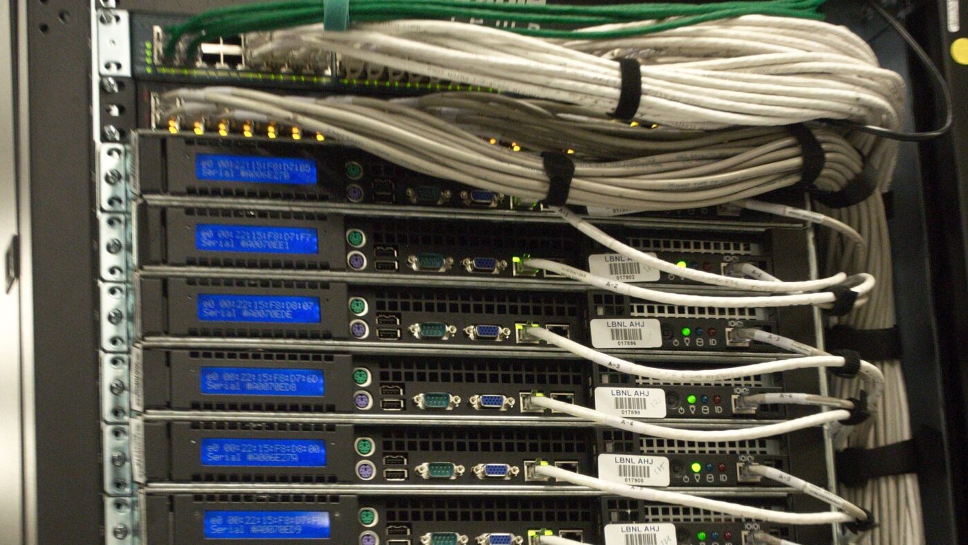 Rückseite eines Serverschranks mit dicht gebündelten Netzwerk- und Stromkabeln in einem Rechenzentrum