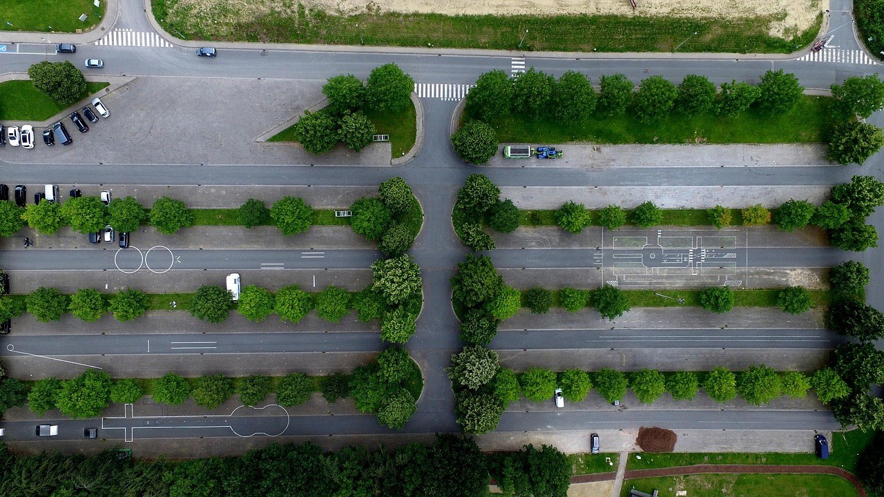 Luftaufnahme eines von Bäumen gesäumten Parkplatzes mit einzelnen abgestellten Autos