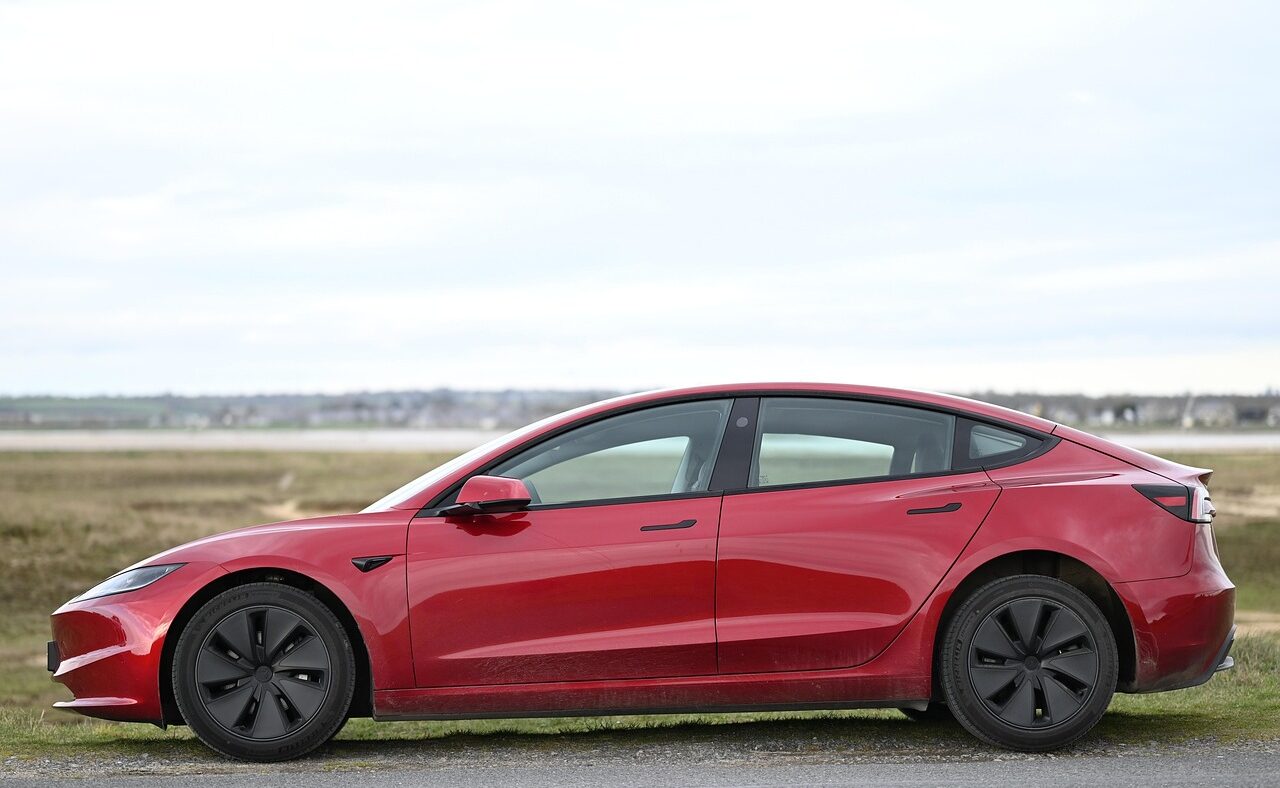 Roter Tesla Model 3 von der Seite fotografiert, Symbolbild zu Tesla Assisted Driving (FSD)